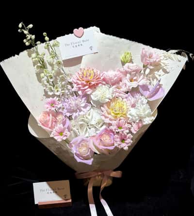 Pink dahlias, blush roses, white carnations and chrysanthemums in a cream paper wrap