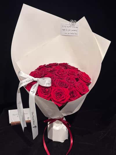 Tall red rose bouquet in ivory paper with a white ribbon bow